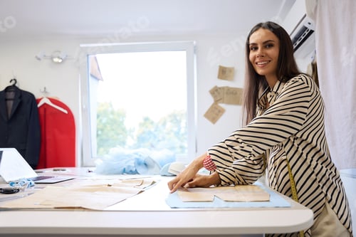 Preview: Pregnant craftswoman lays out patterns on blue fabric