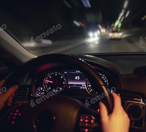 Preview: Car steering wheel and view of the night road from the car, close-up.