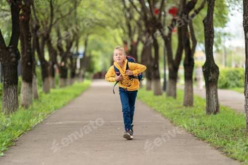 Preview: little boy with a backpack over his shoulders runs with a smile on his face. concept back to school