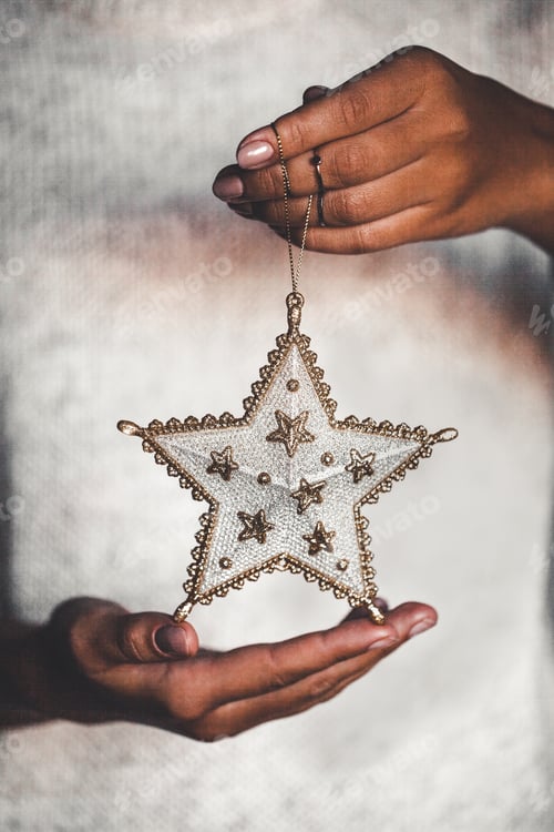 Preview: Woman in warm woolen sweater holding toy glass decorative star in hands, copy space, square crop