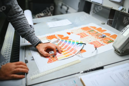Preview: Print house worker controlling printing process quality and checking colors with magnifying glass