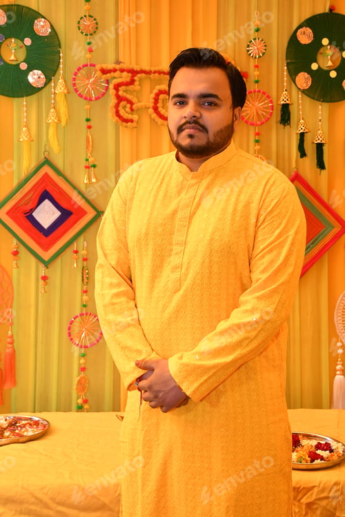 Preview: Man in orange attire at a vibrant Haldi ceremony against a yellow backdrop
