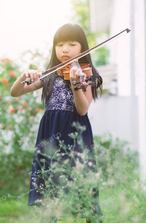 Preview: A cute little girl playing violin in a garden