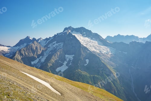 Preview: Dombay Ulgen mountain glacier and green medaow at day.