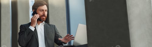 Preview: Businessman talking phone with client during break standing near office building