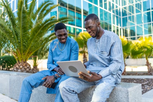 Preview: Senegalese businessmen wearing traditional dashiki using laptop outdoors