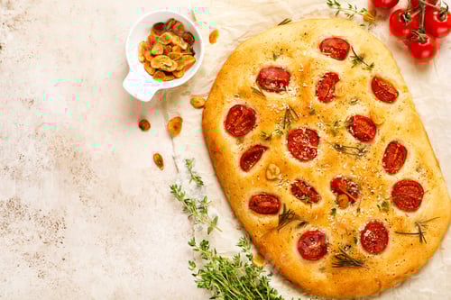 Preview: Italian traditional focaccia bread baking with with cherry tomatoes, parmesan and rosemary on light