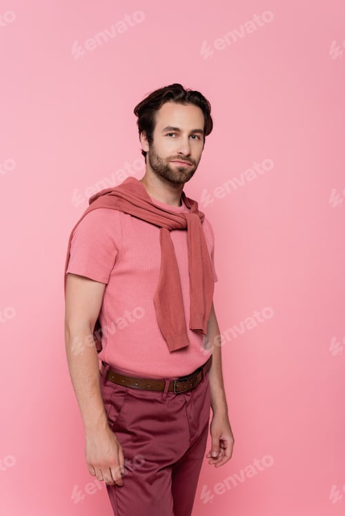Preview: Young man with jumper on shoulders looking at camera isolated on pink