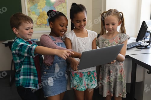 Preview: Group of happy schoolkids studying on laptop in classroom
