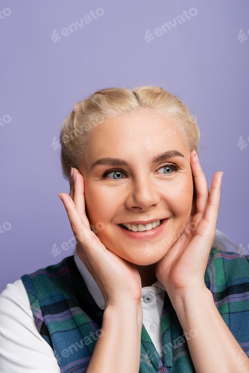 Preview: Portrait of smiling blonde student touching face isolated on purple