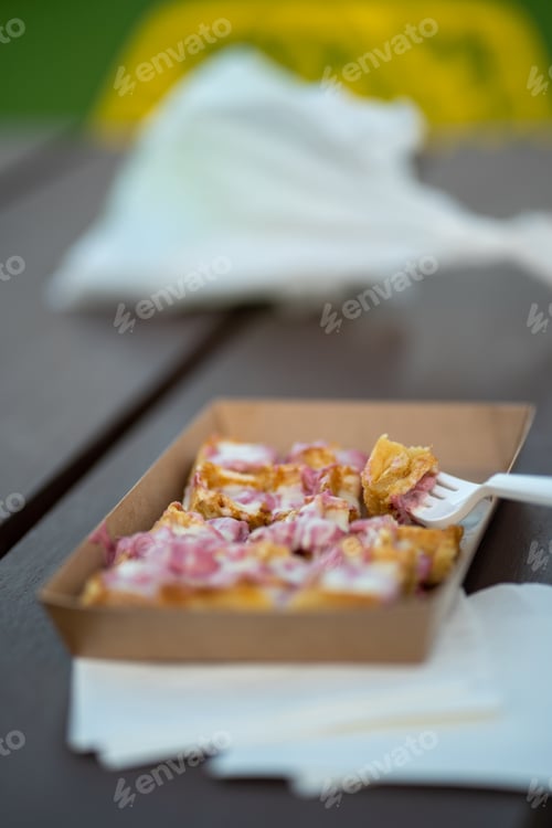 Preview: Vertical closeup of delicious waffles in a carton plate on a wooden bench on a blurred background