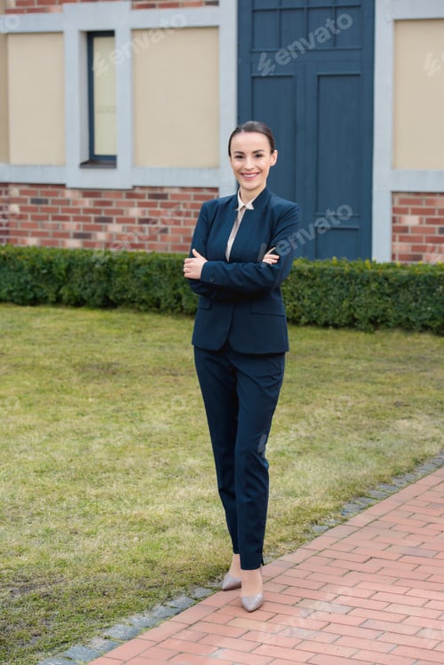 Preview: beautiful businesswoman standing with crossed arms and looking at camera