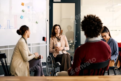 Preview: Happy disabled businesswoman brainstorming with her coworkers during presentation in meeting room.