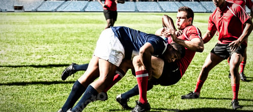 Preview: Digital composite image of team of rugby players tackling each other to win the ball in stadium
