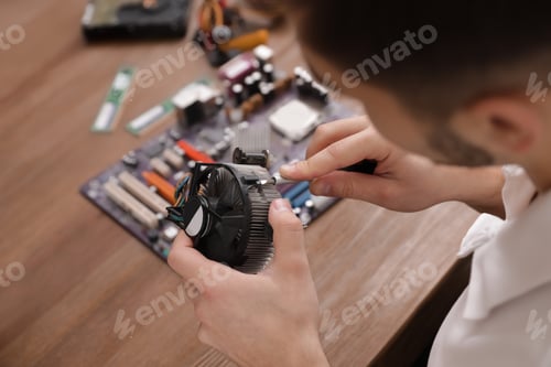 Preview: Male technician repairing computer fan at table, closeup