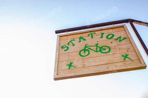 Preview: Wooden sign of a bicycle parking station, isolated against blue sky background.