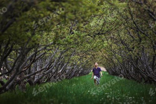 Preview: A child running along a natural woodland tunnel with tree branches forming an arch.
