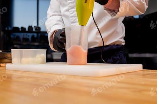 Preview: chef in a white uniform in a professional kitchen mixing salad dressing with green mixer