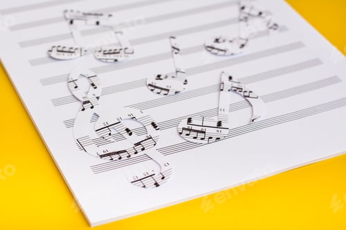 Preview: Blank sheet music and music notes cut from music text on yellow background