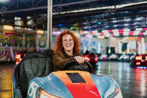 Preview: Young woman enjoying bumper cars at amusement park night