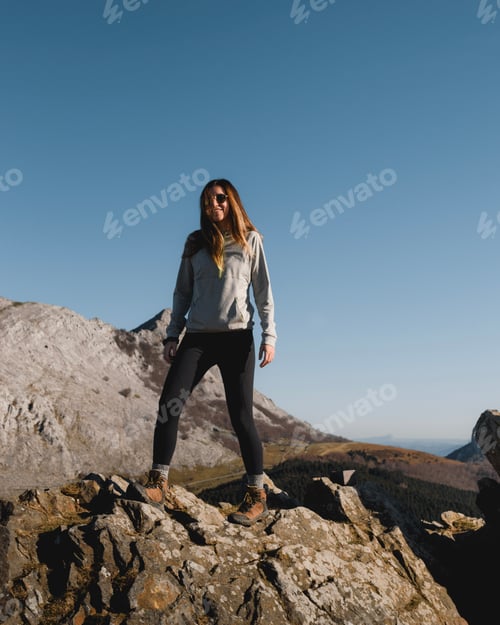 Preview: Tall young girl with long hair smiling standing on a rock