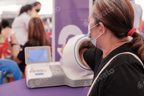 Preview: Fat Asia senior woman inserted her hand into the blood pressure monitor. healthcare and medical