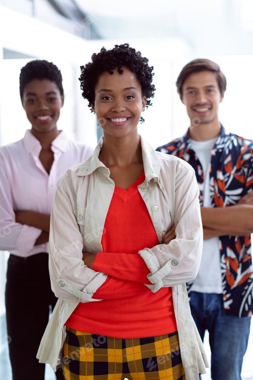 Preview: Front view of young diverse business people with arms crossed looking at camera in a modern office