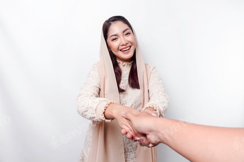 Preview: Young beautiful Asian Muslim woman wearing a headscarf gesturing Eid Mubarak greeting.