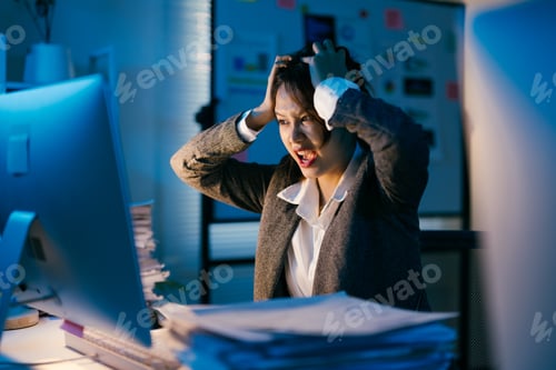 Preview: Young businesswoman is working late at night in office, she is stressed and pulling her hair out whi