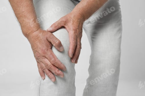 Preview: Senior man having knee problems on grey background, closeup