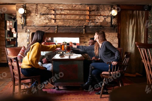 Preview: Group Of Friends Making Toast As They Meet For Lunchtime Drinks In Traditional English Pub