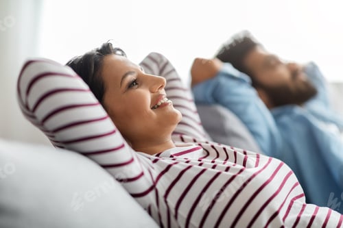 Preview: Relaxed happy young indian couple chilling on couch at home