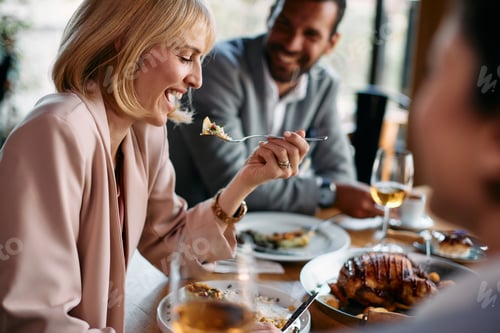 Preview: Happy businesswoman laughing while eating lunch with her colleagues in restaurant.