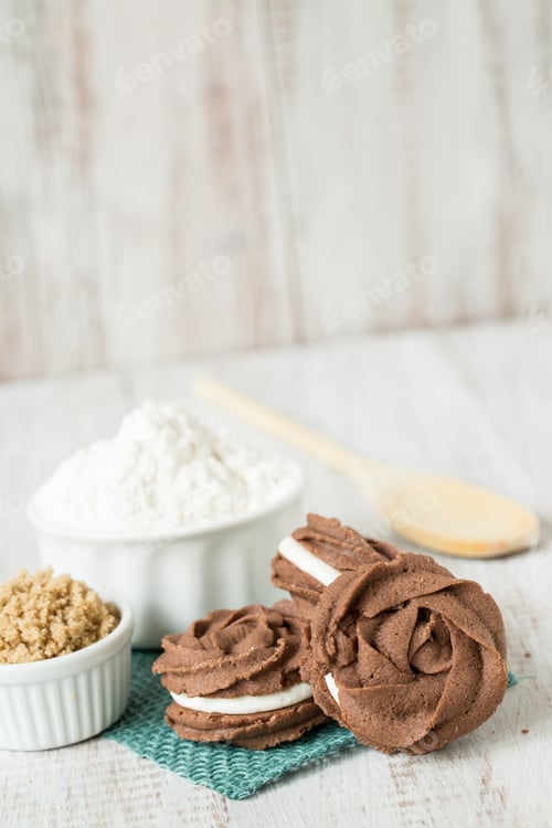 Preview: Chocolate And Vanilla Sandwich Cookies With Flour And Brown Sugar And Wood Spoon