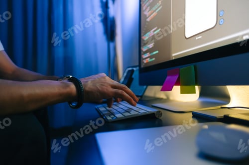 Preview: Mobile developer writes program code on a computer, typing on keyboard