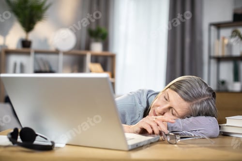 Preview: Elderly woman sleeping near computer in home office
