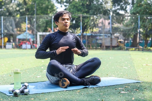 Preview: Man practicing yoga and meditation doing exhaling sitting on a yoga mat