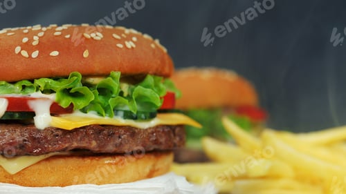 Preview: Fresh homemade grilled burgers and french fries rotating on black smoke background