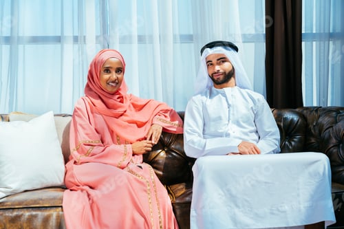 Preview: Happy middle eastern couple wearing traditional arab clothing at home