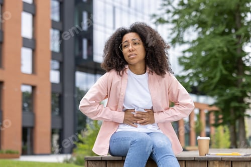 Preview: Young female student experiencing stomach pain near university campus