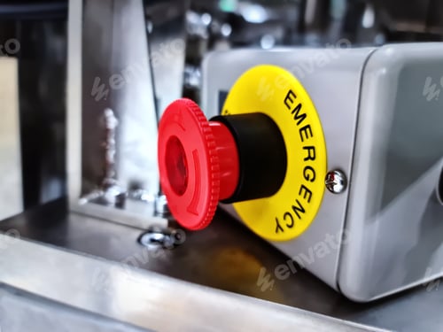 Preview: Close-up Red Emergency Button Against Blurred Machine Background