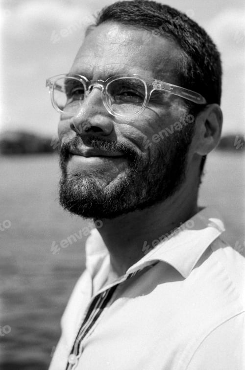 Preview: Bearded man wearing glasses smiling in monochrome analog film portrait