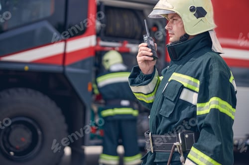 Preview: Man wearing helmet and protective uniform holding walkie in hand