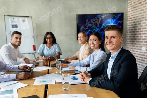 Preview: Modern Business Team. Group Of Multiethnic Colleagues Sitting At Desk In Office