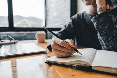 Preview: Close up of student girl hand writing on notebook on a desk at home.