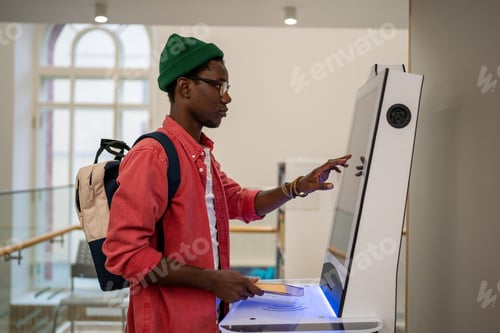 Preview: Progressive young man using self-service electronic terminal to pay in store without salesperson