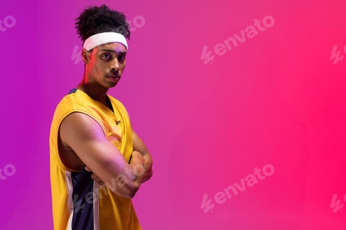 Preview: Man standing arms crossed in studio with yellow jersey and white headband, copy space