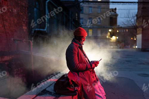 Preview: Smiling african man with smartphone on night street, black guy outdoors chatting in social media