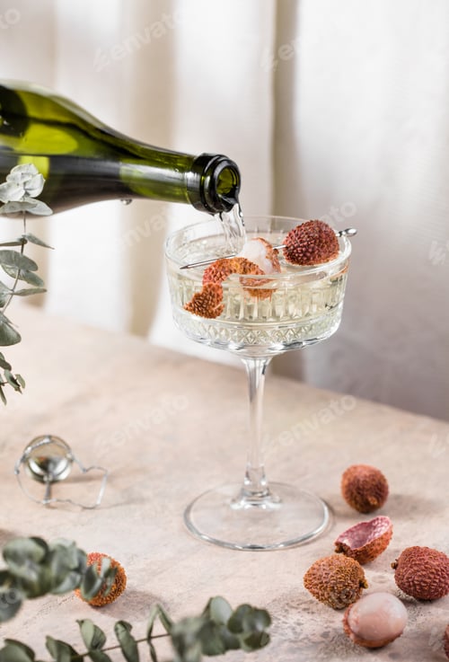 Preview: lychee cocktail with champagne and fresh fruits on a light gray concrete background