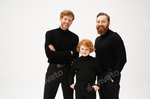 Preview: joyful redhead kid standing with hands in pockets near bearded dad and grandfather isolated on grey